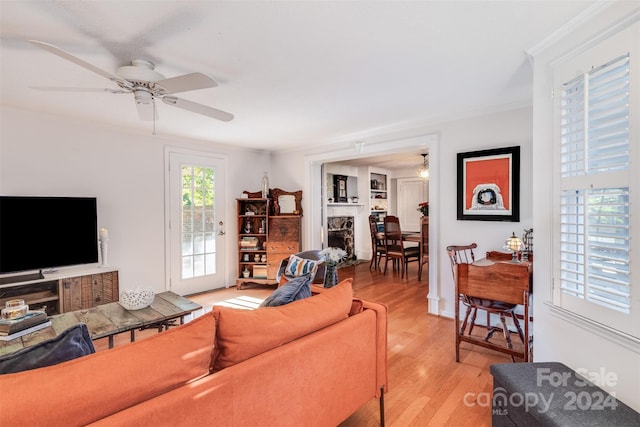 living room featuring ceiling fan, crown molding, and light hardwood / wood-style flooring