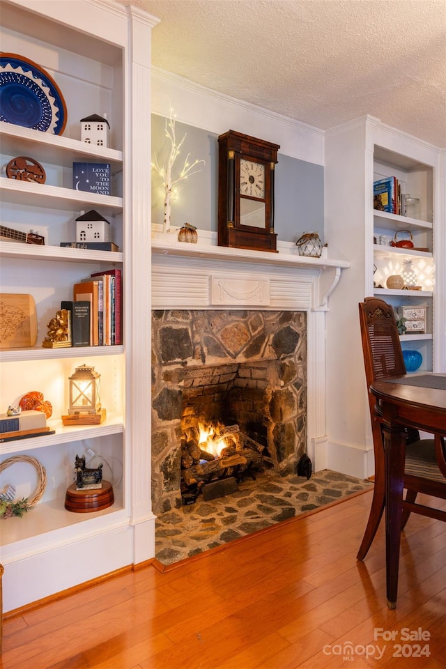 details featuring a fireplace, built in features, a textured ceiling, hardwood / wood-style floors, and crown molding