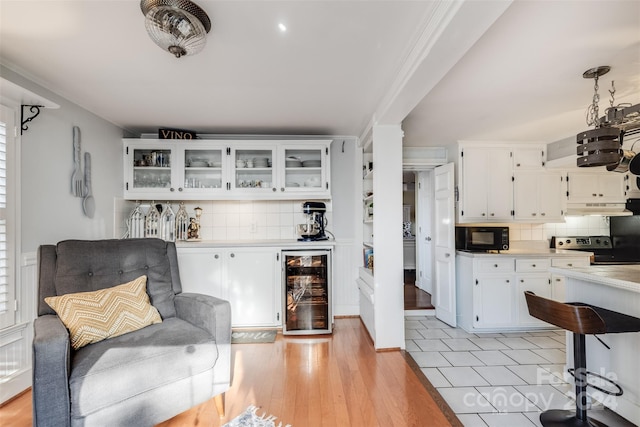 interior space with wine cooler, light hardwood / wood-style flooring, and bar area