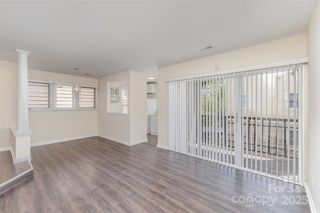 unfurnished living room with visible vents, baseboards, ornate columns, and wood finished floors