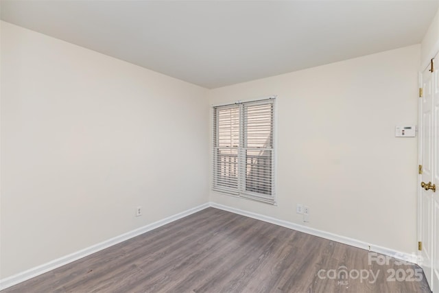 unfurnished room with baseboards and dark wood-style floors