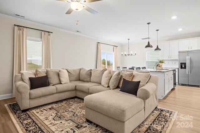 living room with ornamental molding, ceiling fan with notable chandelier, light hardwood / wood-style floors, and sink