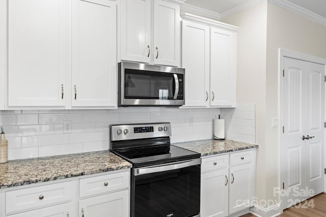 kitchen featuring light stone counters, ornamental molding, white cabinetry, light wood-type flooring, and appliances with stainless steel finishes