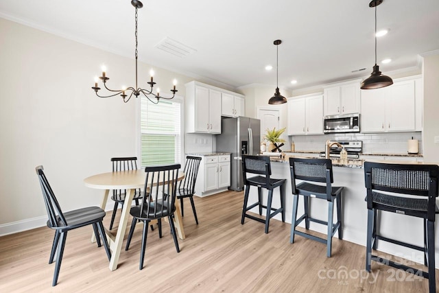 kitchen with white cabinetry, appliances with stainless steel finishes, light stone counters, and pendant lighting