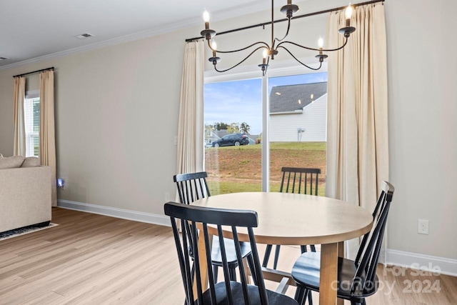 dining space with ornamental molding, a wealth of natural light, and light hardwood / wood-style flooring