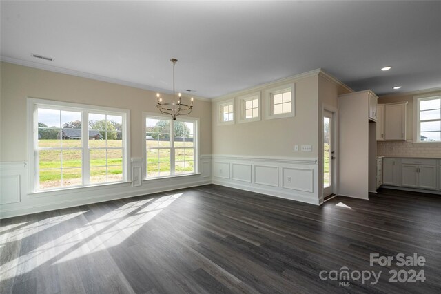 unfurnished dining area featuring ornamental molding, dark wood-type flooring, and a chandelier