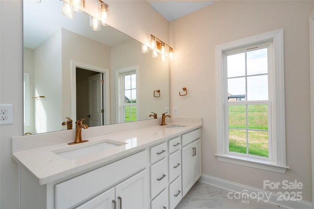 bathroom with marble finish floor, a sink, baseboards, and double vanity