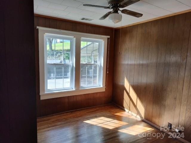 unfurnished room featuring wooden walls, hardwood / wood-style flooring, and ceiling fan