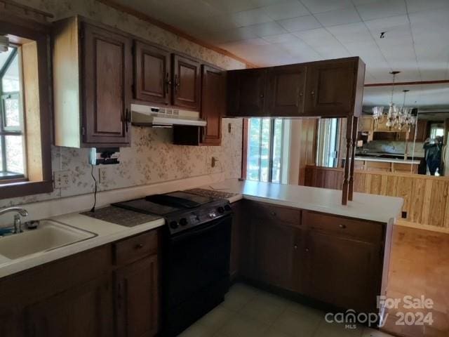 kitchen with sink, dark brown cabinets, electric range, kitchen peninsula, and hanging light fixtures