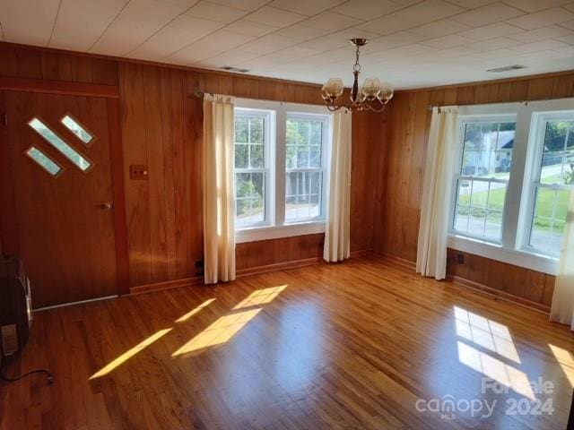 entryway featuring hardwood / wood-style flooring, wooden walls, and a chandelier