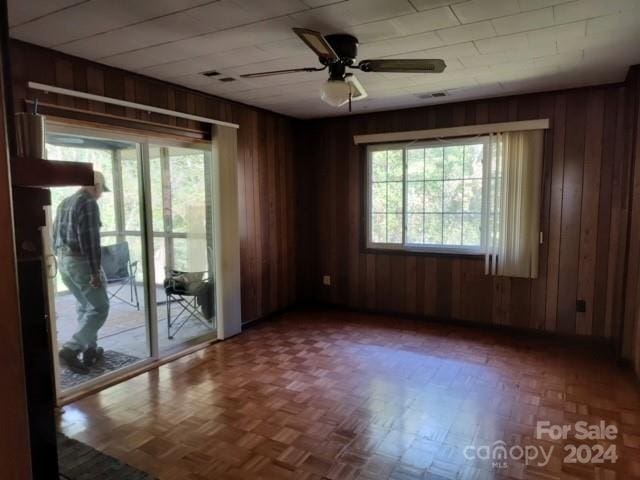 spare room featuring wood walls and ceiling fan