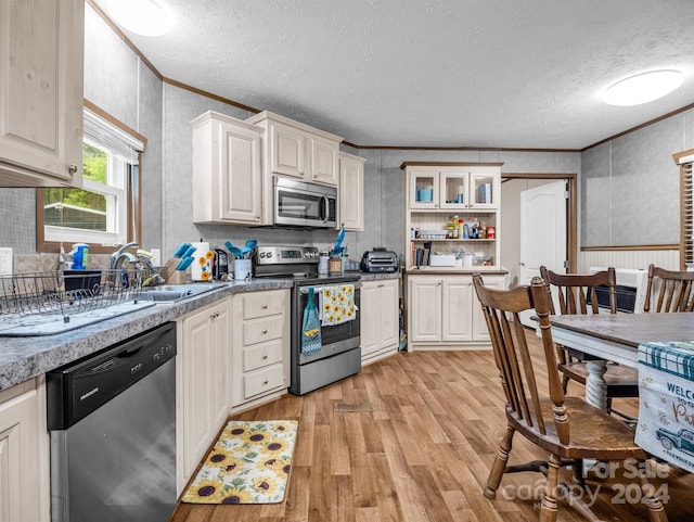 kitchen featuring sink, crown molding, light wood-type flooring, appliances with stainless steel finishes, and a textured ceiling