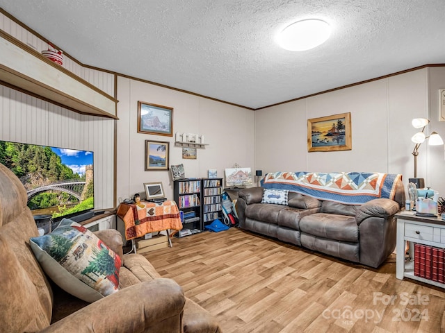 living room featuring ornamental molding, a textured ceiling, and light wood-type flooring