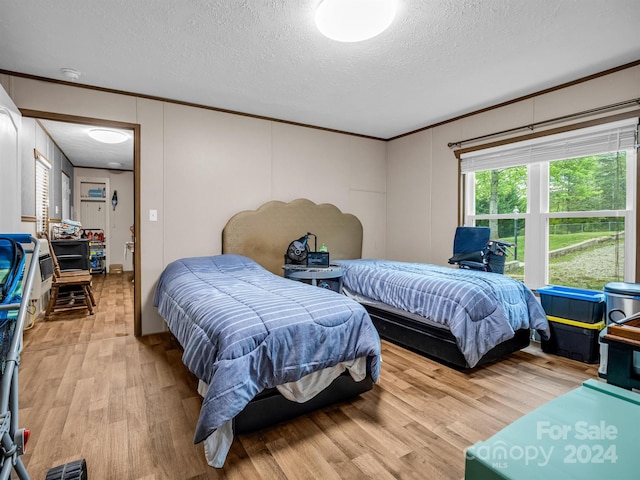 bedroom featuring crown molding, a textured ceiling, and wood-type flooring