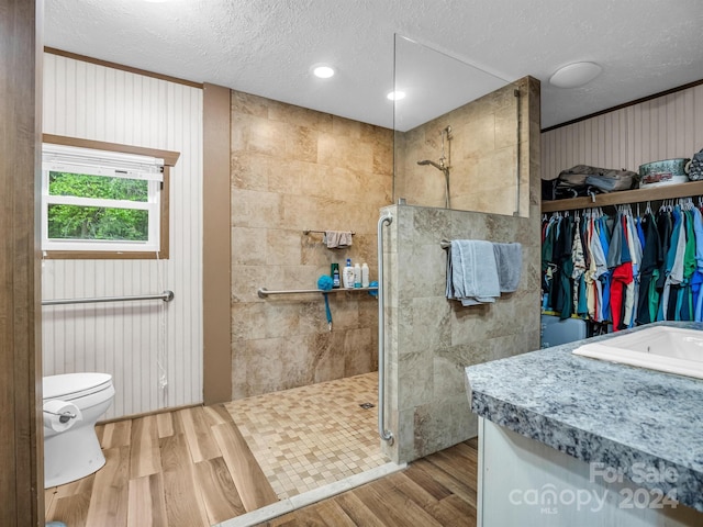 bathroom with vanity, tiled shower, wood-type flooring, and toilet