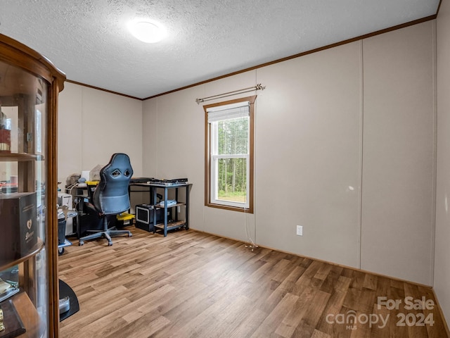 office with a textured ceiling, ornamental molding, and light wood-type flooring