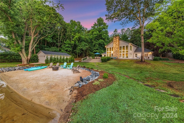 yard at dusk with a patio, an outdoor fire pit, a deck, and an outbuilding