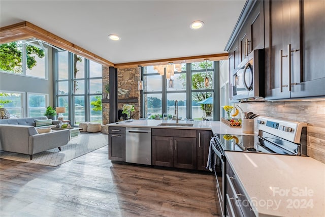 kitchen with dark brown cabinets, dark hardwood / wood-style floors, stainless steel appliances, sink, and light stone counters