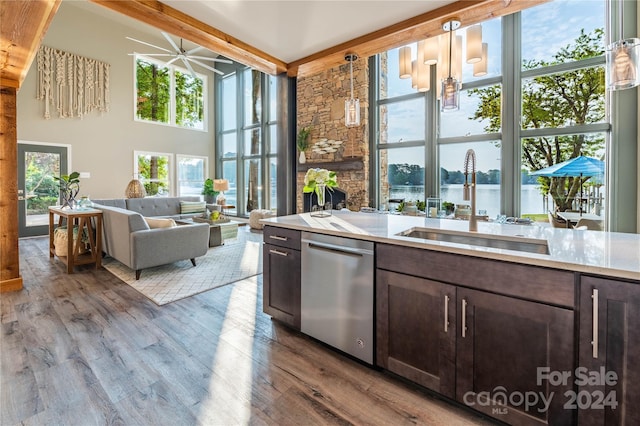 kitchen with dishwasher, sink, pendant lighting, a water view, and light hardwood / wood-style flooring