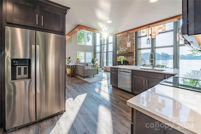 kitchen featuring sink, dark brown cabinets, stainless steel appliances, light stone counters, and dark hardwood / wood-style floors