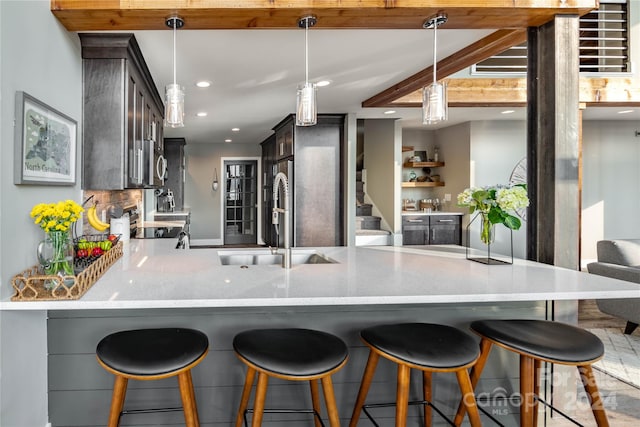 kitchen with sink, dark brown cabinetry, pendant lighting, and tasteful backsplash