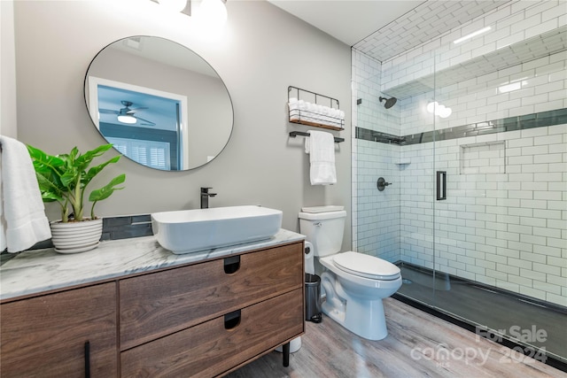 bathroom with a shower with door, hardwood / wood-style flooring, toilet, vanity, and ceiling fan