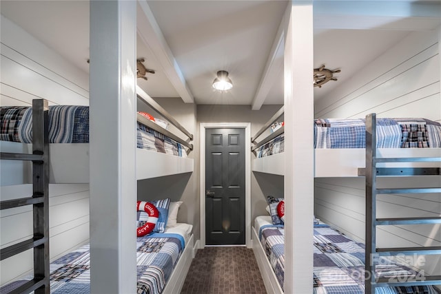 bedroom with beam ceiling and wooden walls