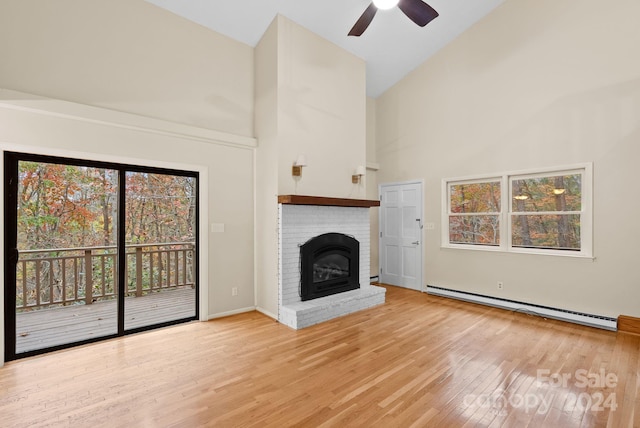 unfurnished living room with light wood-type flooring, baseboard heating, ceiling fan, high vaulted ceiling, and a fireplace