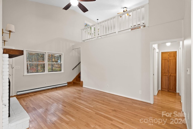 unfurnished living room featuring light hardwood / wood-style flooring, high vaulted ceiling, a baseboard radiator, and plenty of natural light