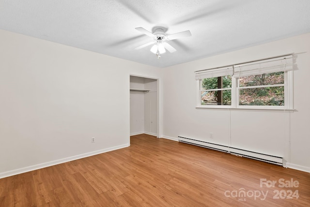 unfurnished bedroom featuring a textured ceiling, ceiling fan, a baseboard heating unit, light hardwood / wood-style floors, and a closet