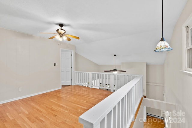 staircase with ceiling fan, wood-type flooring, and vaulted ceiling