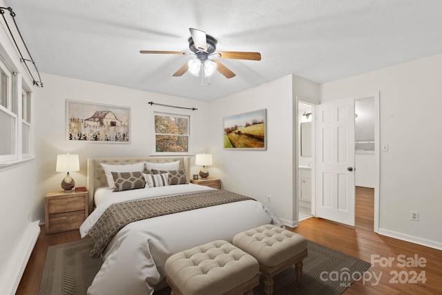 bedroom featuring ensuite bath, ceiling fan, dark wood-type flooring, and a textured ceiling