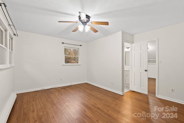 empty room featuring ceiling fan, wood-type flooring, and a textured ceiling