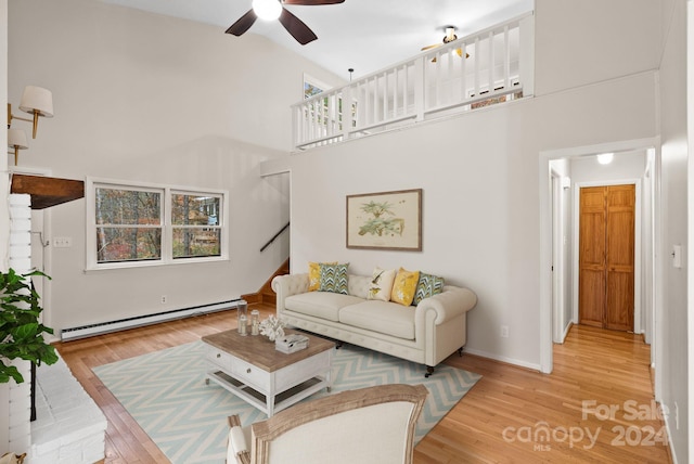 living room with baseboard heating, ceiling fan, high vaulted ceiling, and light hardwood / wood-style floors