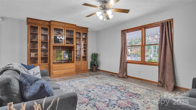 living room with a textured ceiling, light wood-type flooring, and ceiling fan