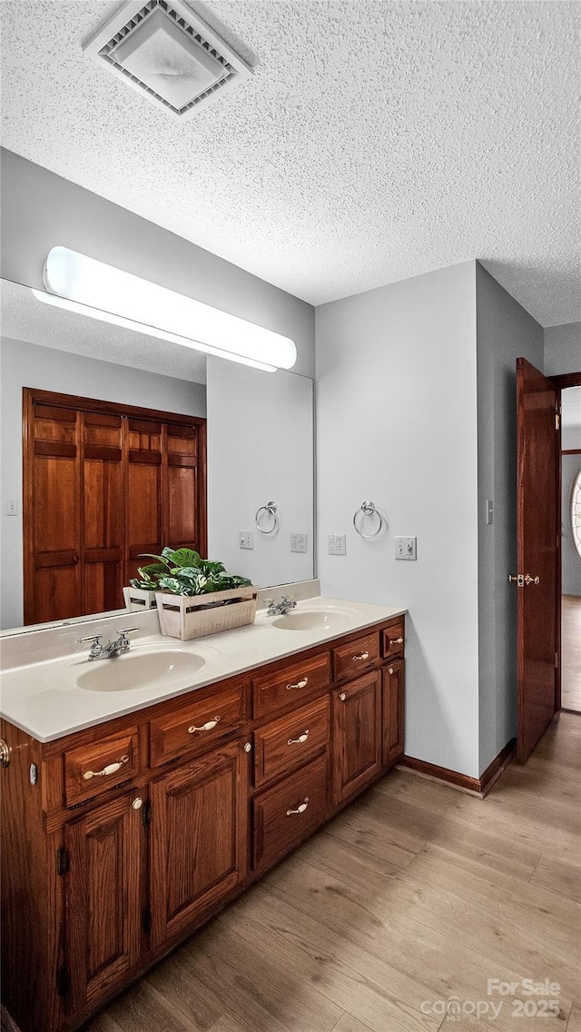 bathroom featuring hardwood / wood-style floors, vanity, and a textured ceiling