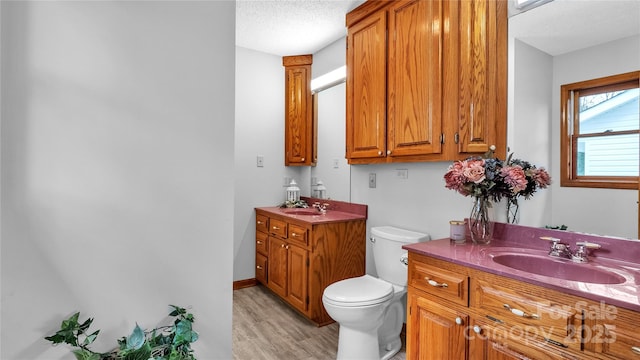 bathroom with vanity, toilet, wood-type flooring, and a textured ceiling