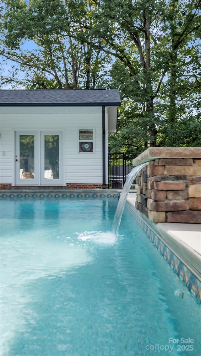 view of swimming pool featuring pool water feature and an outdoor structure