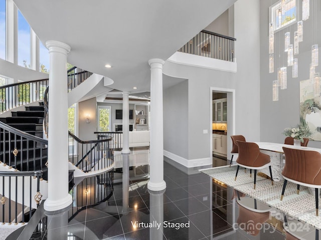 stairway with a healthy amount of sunlight, decorative columns, and a high ceiling