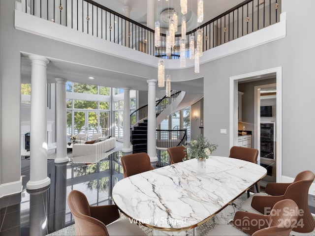 dining space featuring a towering ceiling, a chandelier, beverage cooler, and ornate columns