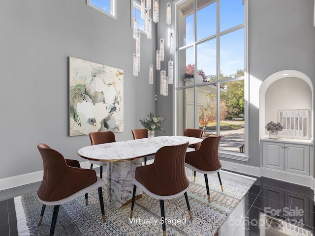 dining area with dark tile patterned flooring and a high ceiling