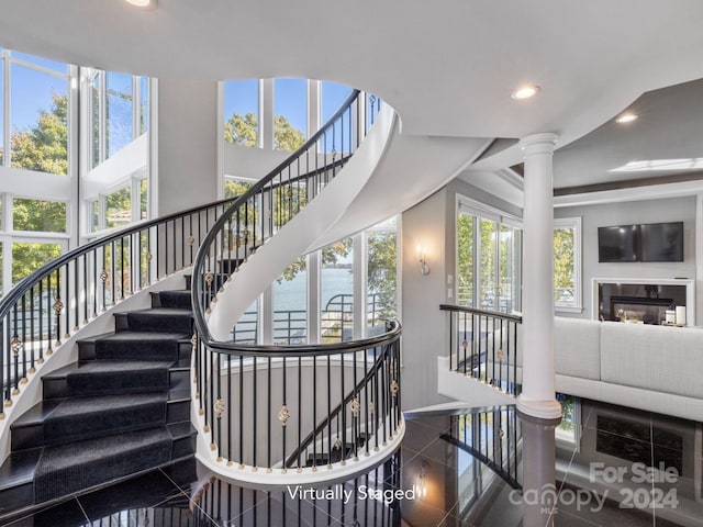 stairs featuring ornate columns, tile patterned floors, and plenty of natural light