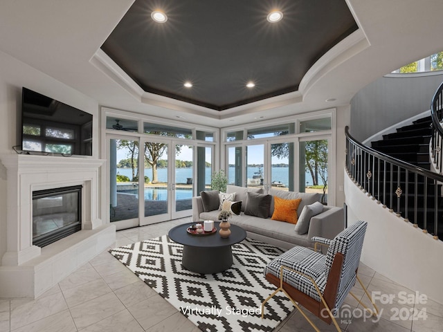 living room featuring a water view, a raised ceiling, french doors, and a wealth of natural light