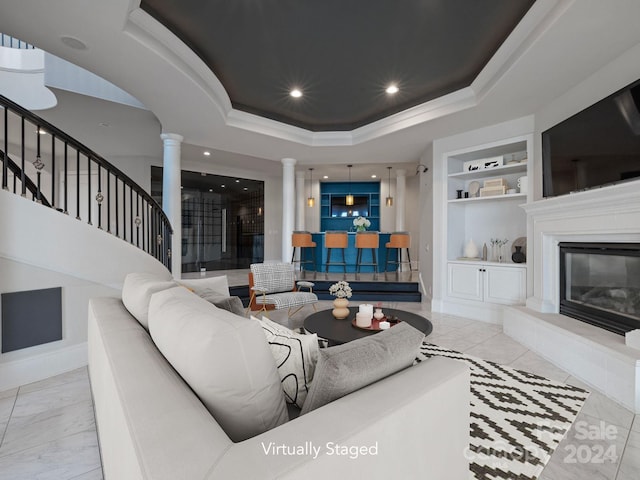 living room featuring light tile patterned flooring, decorative columns, a tray ceiling, and built in shelves