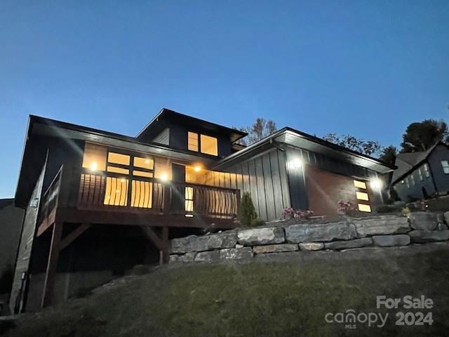 back house at dusk featuring a wooden deck