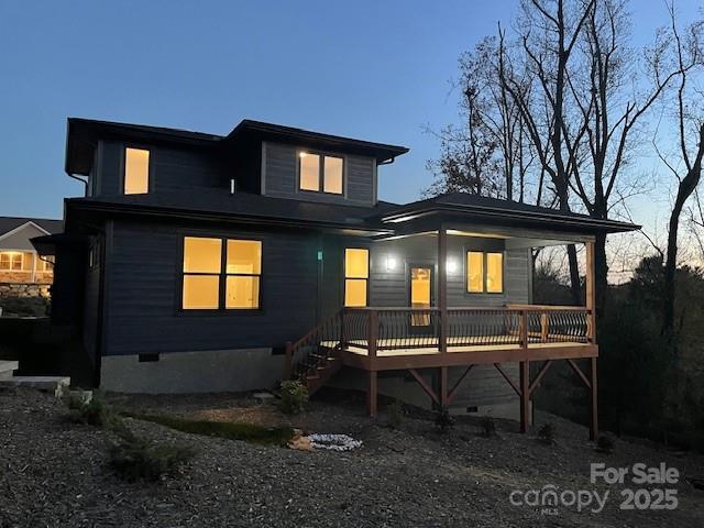 back house at dusk featuring a wooden deck