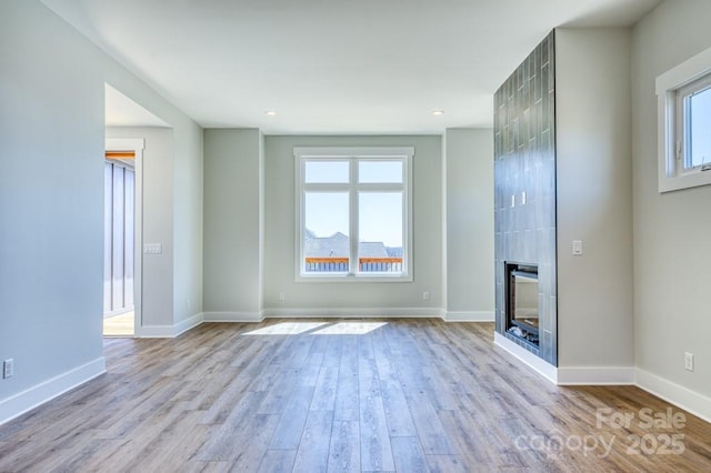 unfurnished living room featuring plenty of natural light, light hardwood / wood-style flooring, and a fireplace