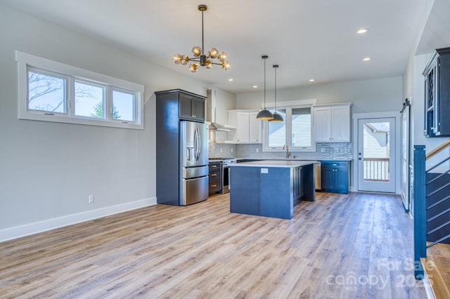 kitchen featuring white cabinetry, stainless steel appliances, backsplash, hanging light fixtures, and a kitchen island