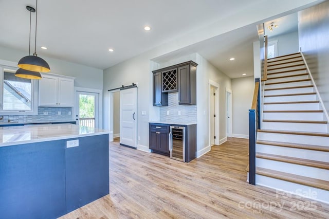 kitchen featuring hanging light fixtures, a barn door, beverage cooler, and backsplash