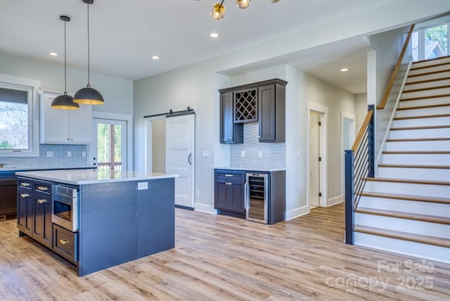 kitchen with pendant lighting, a center island, wine cooler, decorative backsplash, and a barn door